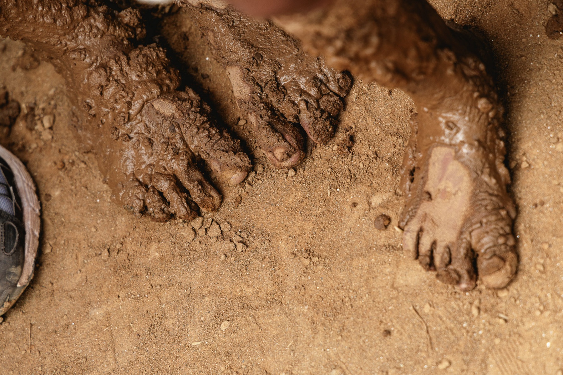 Mud-caked hands and feet of a brick kiln worker