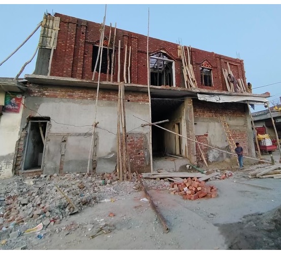 The school building mid-construction — bare brick and scaffolding