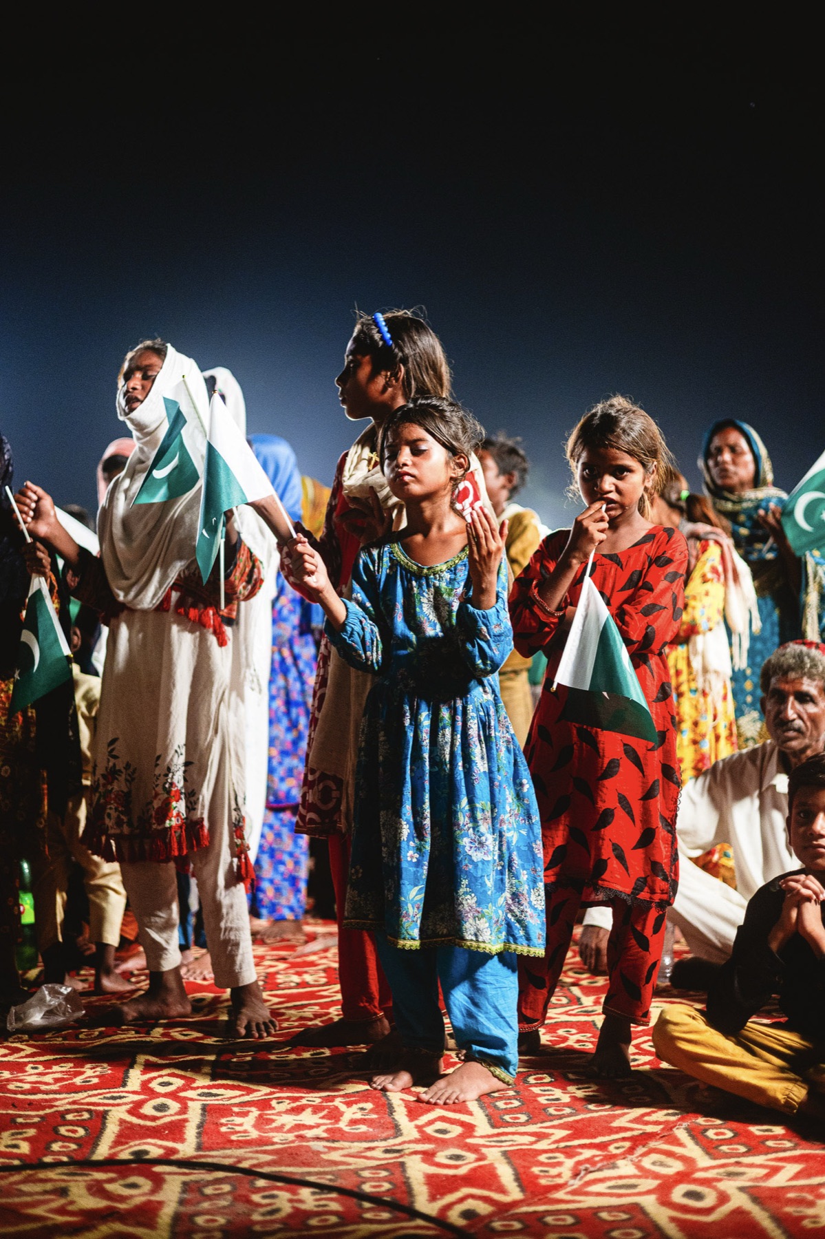 Women worship with raised hands at a night service